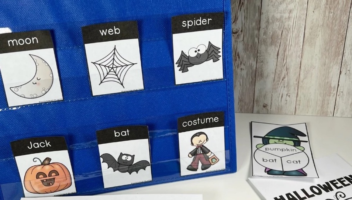 Halloween vocabulary cards in a blue pocket chart beside a topic spinner and writing pages